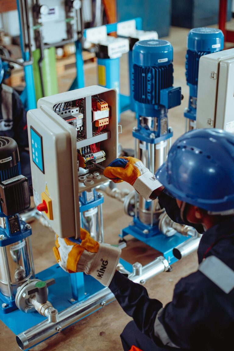 Engineers inspect pumps, valves, and interconnected process piping inside a clean manufacturing facility.