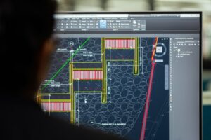 Mechanical engineer reviewing piping plans beside pumps, valves, tanks, and industrial process equipment.